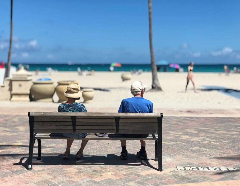 pexels-photo-1034597-1034597 Senior couple sitting on a bench enjoying a sunny day at Hollywood Beach, Florida.