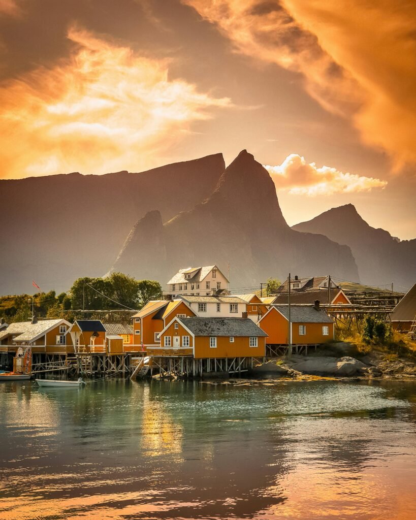 Scenic view of a colorful village by the fjord against a dramatic sunset in Vågan, Nordland, Norway.