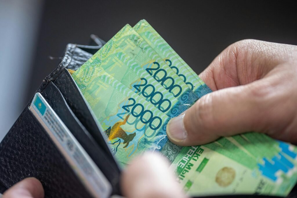 Close-up of hand holding 2000 Kazakhstan Tenge banknotes in a wallet.