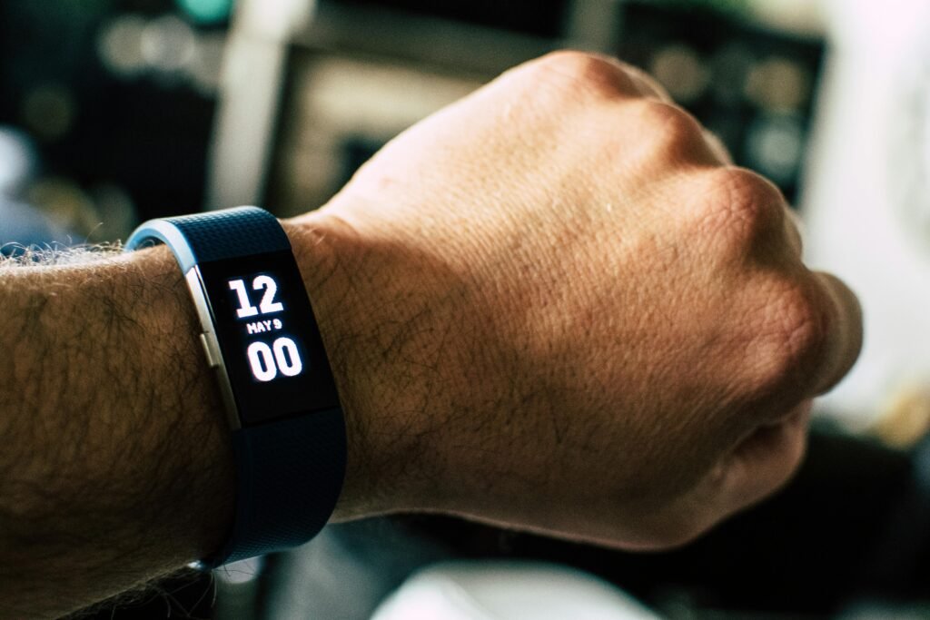 A close-up image of a wristwatch displaying 12:00 noon with a blurred background.