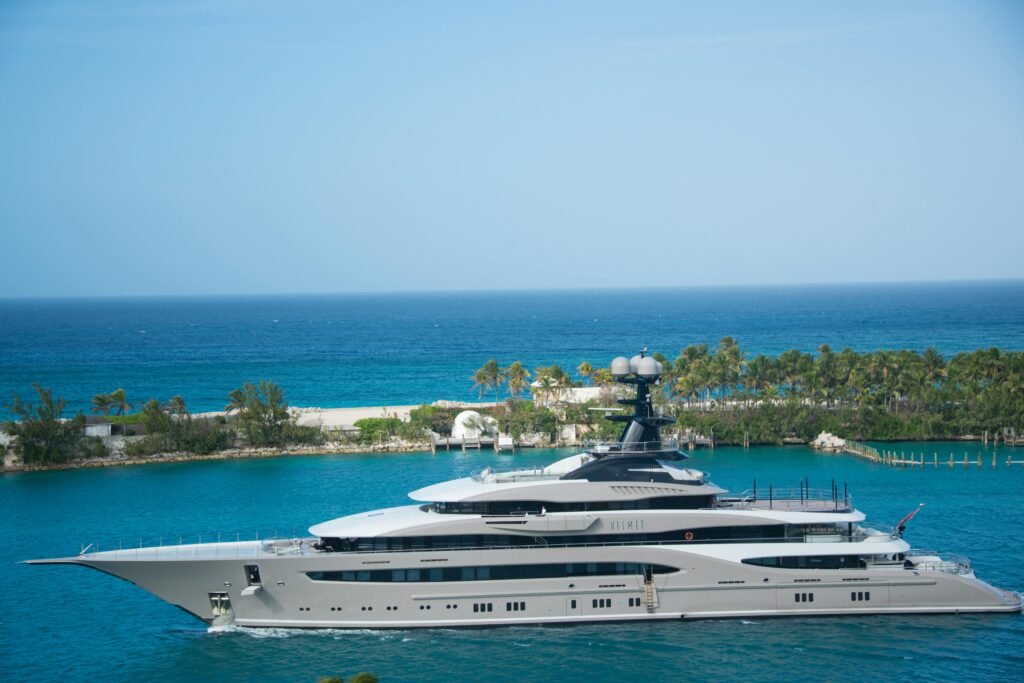 High-end yacht cruising along a tropical coastline with clear blue waters and lush greenery.