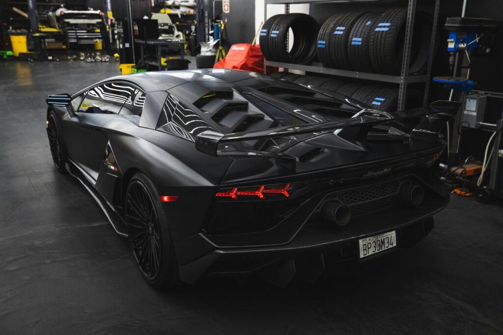 Sleek black Lamborghini Aventador SVJ parked indoors, showcasing luxury and power.
